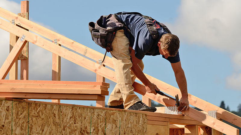 Construction worker building the roof of a house before home inspection services are scheduled 