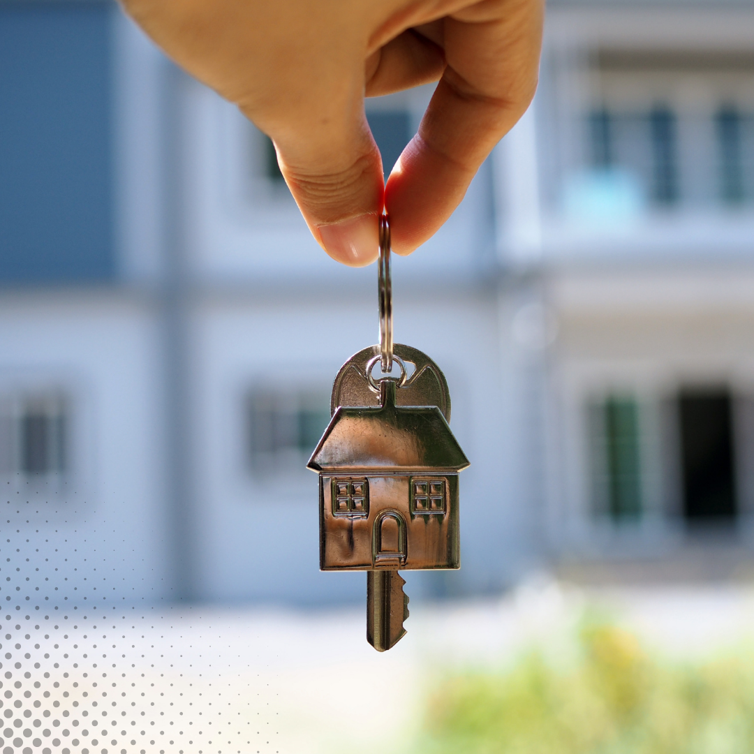 A hand grasps a house-shaped keychain along with a key 