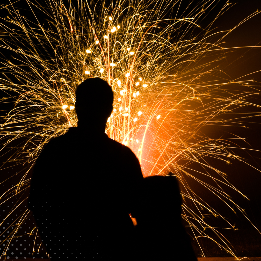 Watching a brilliant fireworks display, a person stands in silhouette