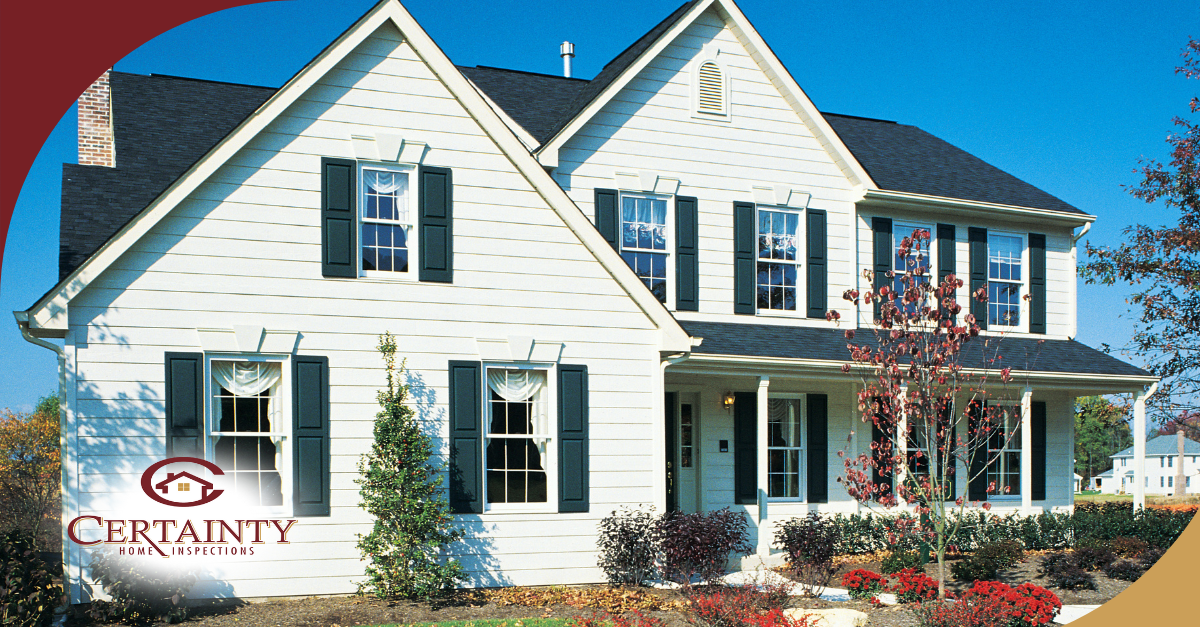 Classic two-story home with white siding and black shutters, surrounded by a neatly landscaped yard