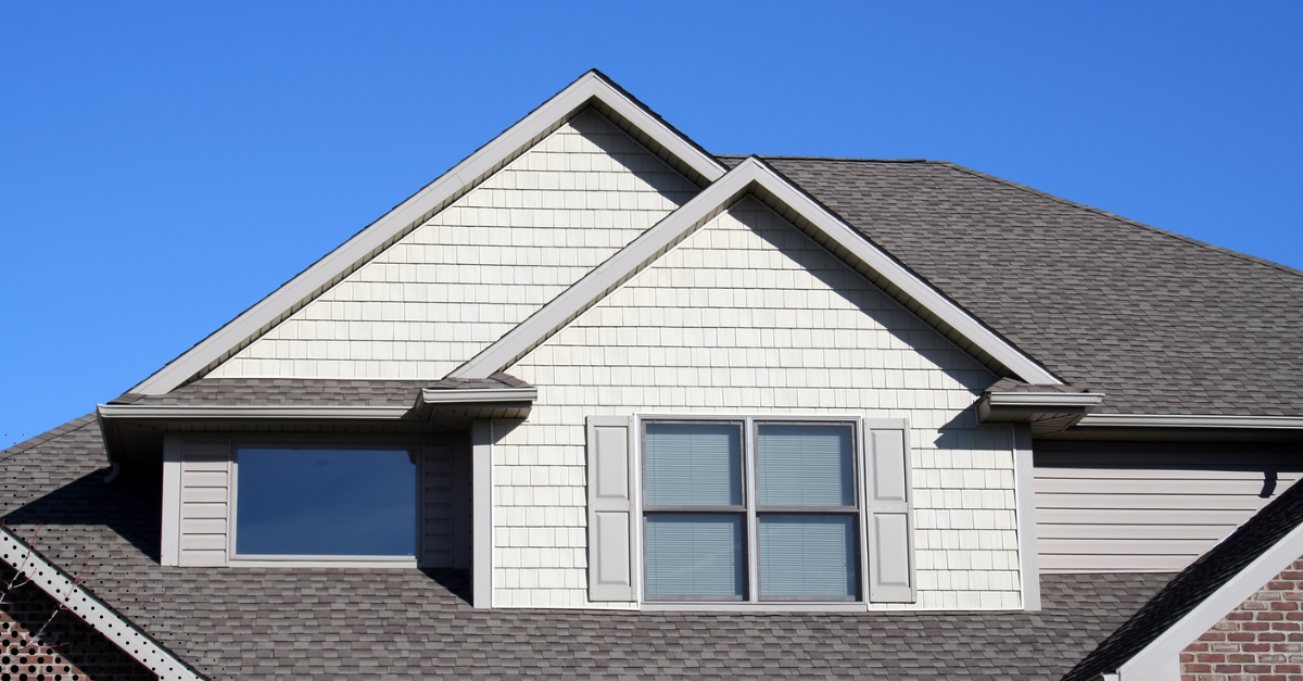 Close-up of a home’s exterior gable and roof, highlighting the siding and shingle condition 