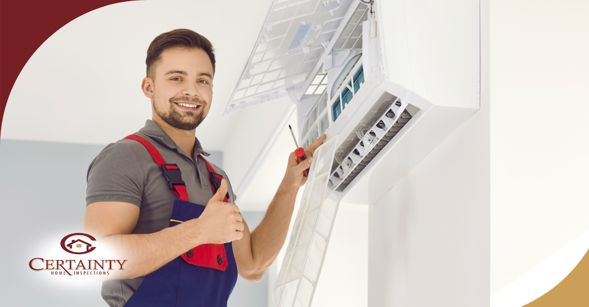 A smiling technician giving a thumbs-up while inspecting or servicing an air conditioning unit.