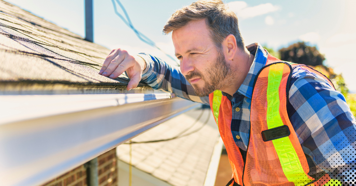 Roof inspector examining shingles for damage during a home inspection
