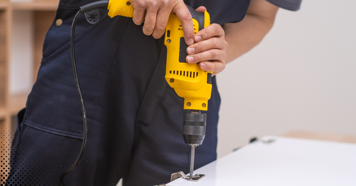 Handyman using a power drill to install a hinge.
